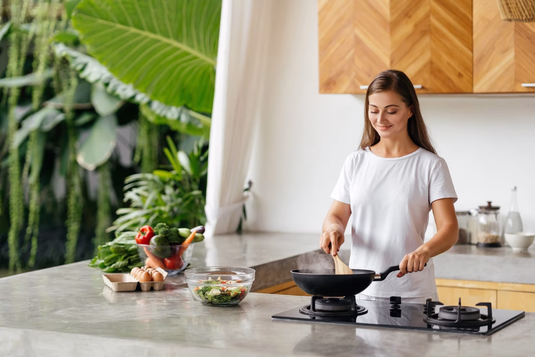 Young woman cooking in the open kitchen. Healthy Food. Dieting Concept. Healthy Lifestyle. Cooking At Home. Prepare Food